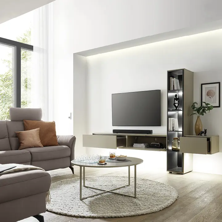 Helles Wohnzimmer mit TV-Wand, schmalem Regal, rundem Couchtisch und grauem Sofa